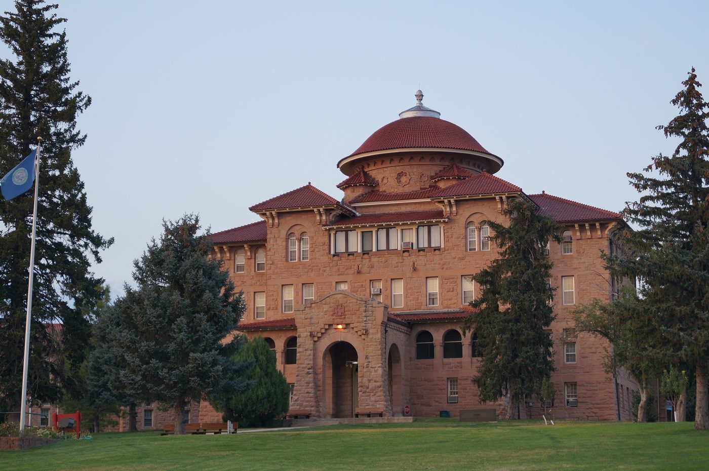 The historic Battle Mountain Sanitarium building, a red-roofed sandstone building among pine trees in Hot Springs
